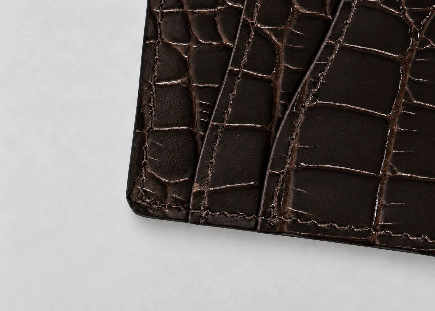 Close-up of the espresso crocodile-effect surface and stitched card pockets.