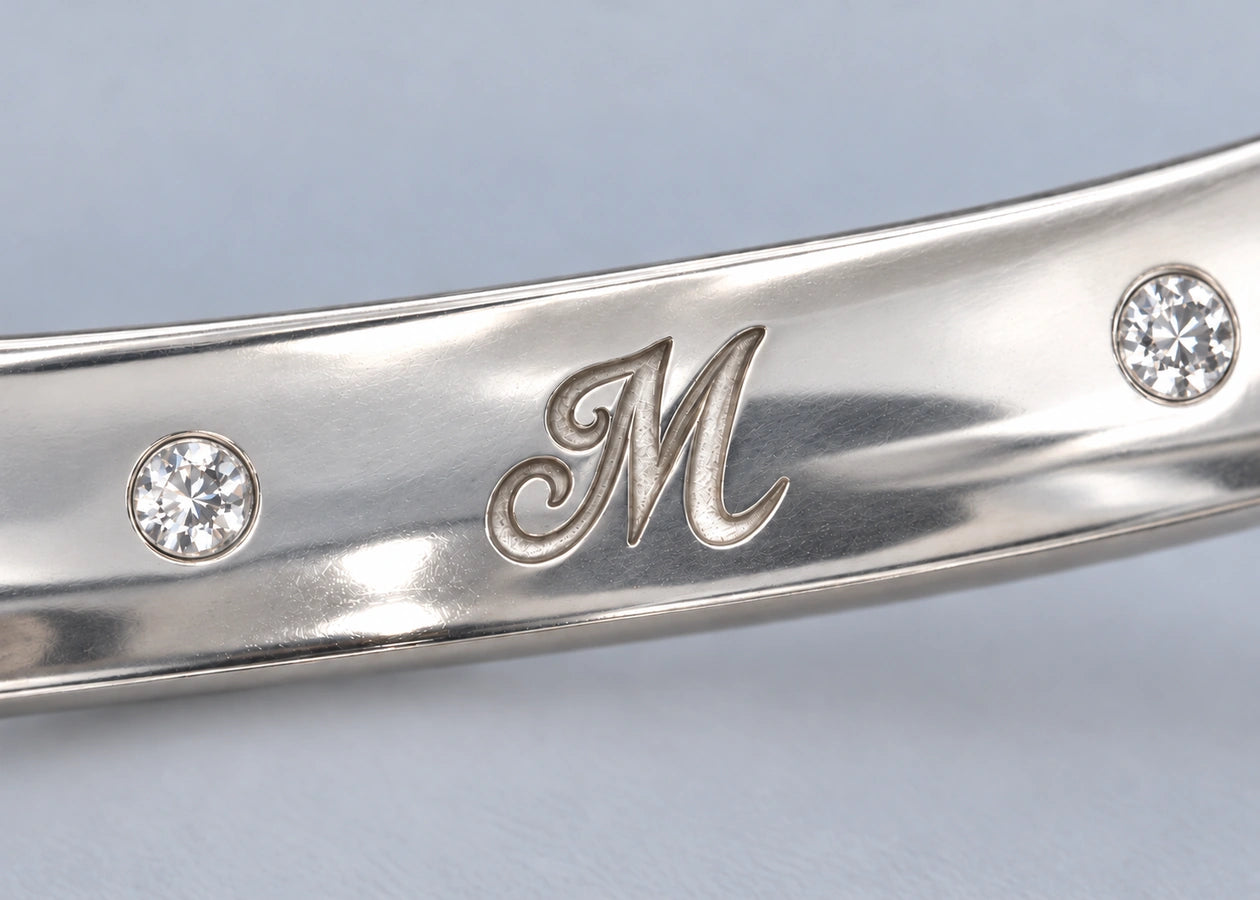 Two diamonds frame the engraved M inside the silver ring.