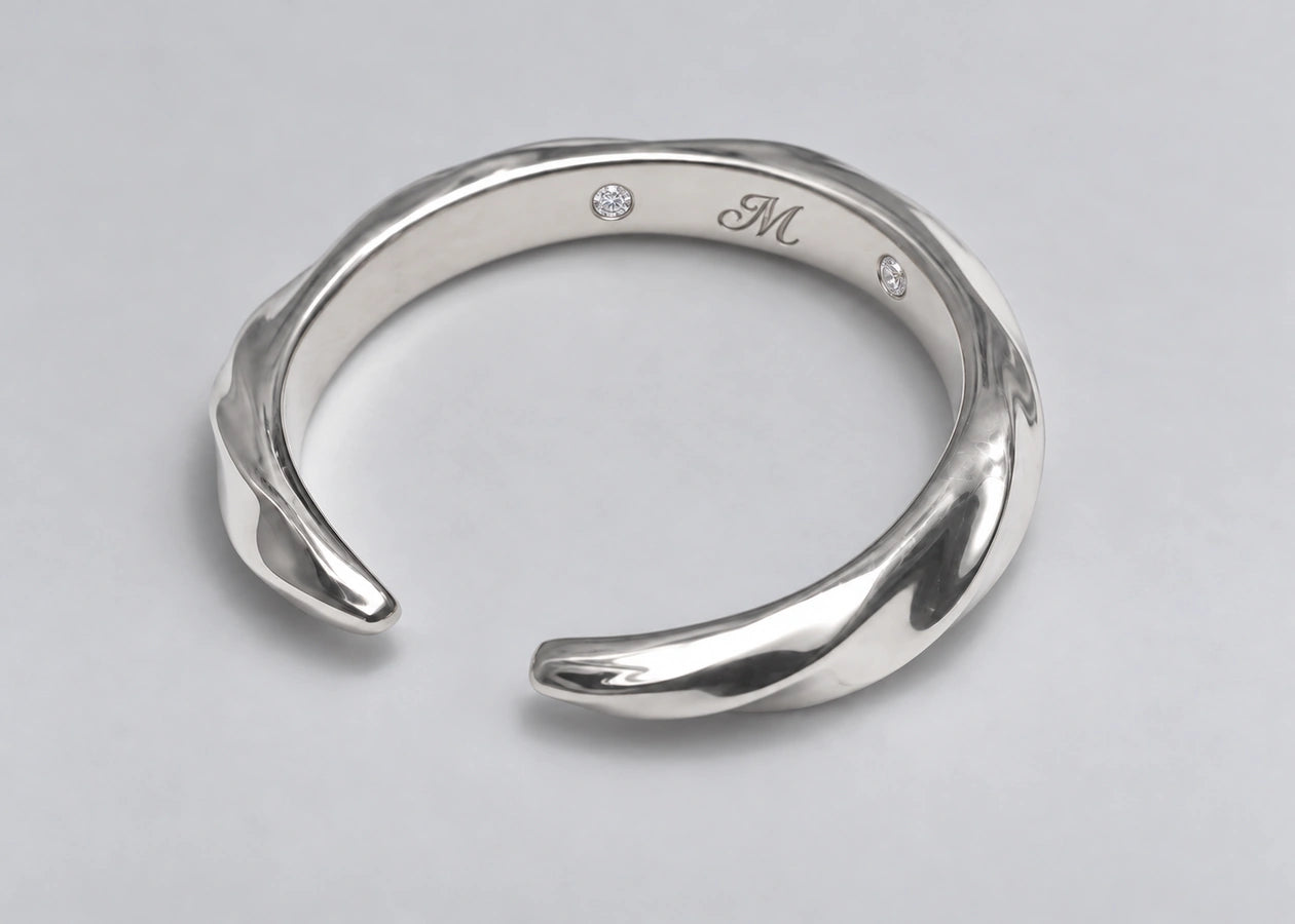 Open silver ring with its two tapered ends and inner signature visible.